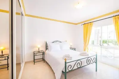 a white bedroom with a bed and a large window at Villa Redonda in Albufeira