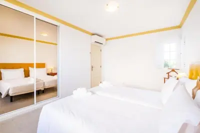 a white bedroom with two beds and a mirror at Villa Redonda in Albufeira