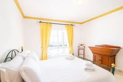 a bedroom with a white bed and a piano at Villa Redonda in Albufeira