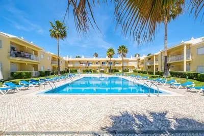 a swimming pool with lounge chairs and palm trees at Apartment Riu - Close to bars shops and restaurants in Albufeira