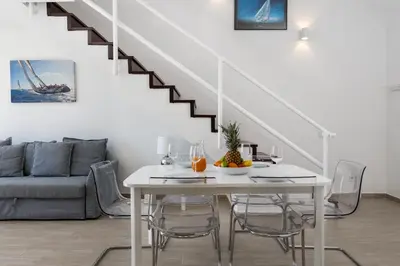 a white dining room with a white table and a staircase at Marina Vision Vilamoura in Vilamoura