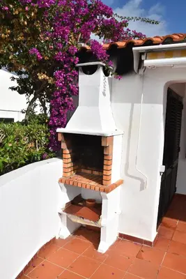 a table with four chairs and a table with a plant on it at Casa Linda da Praia do Alfamar in Albufeira