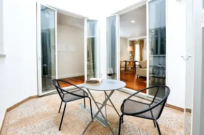 a table and two chairs in a room with glass walls at Green Algarve Gem Spacious 2 BDR By Misha's Place in Faro