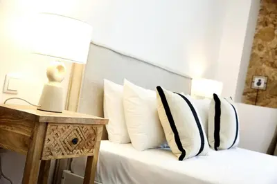 a bedroom with a bed with white pillows and a table at GREEN BLISS IN FARO, Central One-Bed Oasis in Faro
