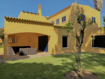 a yellow house with a tree in the yard at Fashion Villa in Vilamoura with Private Pool in Quarteira