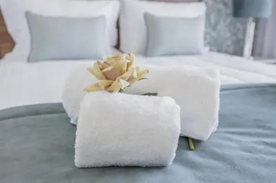 a pile of towels and a flower on a bed at Terracos de Quarteira II Eden by Real Properties in Quarteira
