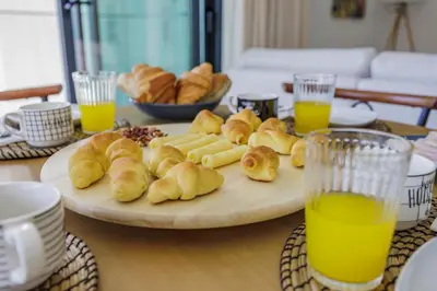 a table with a plate of pastries and orange juice at Terraços de Quarteira II Frolic by Real Properties in Cavacos