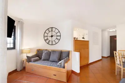a living room with a couch and a clock on the wall at Ema Clube em Albufeira in Albufeira