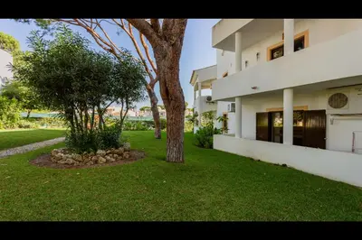 a building with two trees and a grass yard at Falésia Modern Flat W/Balcony & Pool by LovelyStay in Albufeira
