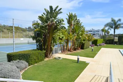 a tennis court with palm trees and a tennis court at Casa Paula in Quarteira
