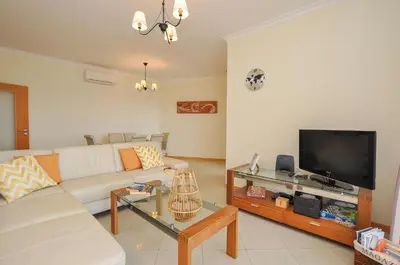 a living room with a white couch and a tv at Encosta da Orada by OCvillas in Albufeira