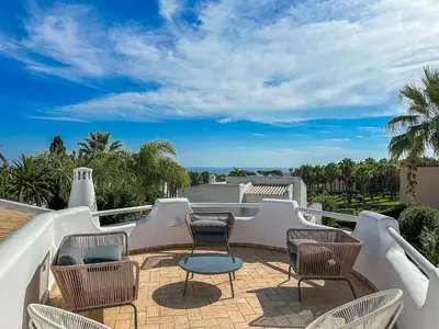 a patio with chairs and tables on a balcony at Luxury Villa Heated Pool, walk to São Rafael Beach, Albufeira in Albufeira