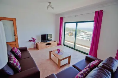 a living room with a television and a view of the beach at Dalia in Quarteira