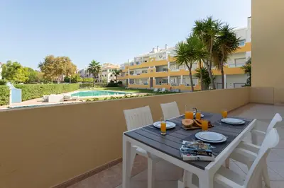 a table and chairs on the balcony of a apartment at Centralgarve - Spacious & Elegant - Vilamoura w Pool - Jacarandás in Quarteira
