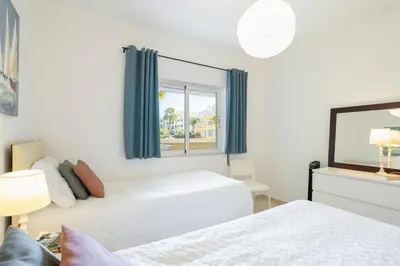 a white bedroom with two beds and a window at Centralgarve - Spacious & Elegant - Vilamoura w Pool - Jacarandás in Quarteira