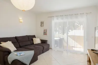a living room with a brown couch and a sliding glass door at Centralgarve - Spacious & Elegant - Vilamoura w Pool - Jacarandás in Quarteira