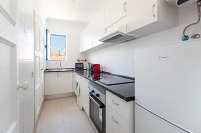 a kitchen with white cabinets and a black counter top at Centralgarve - Cosy&Central 1bdrm in Vilamoura - Pateos da Marina in Vilamoura