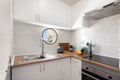 a kitchen with white cabinets and a sink and a mirror at Apartment Montechoro in Albufeira