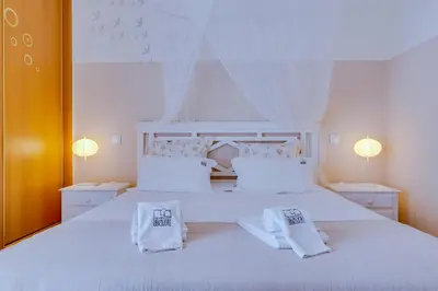 a white bedroom with a white bed with two pillows at Falésia Nature Villa by The Portuguese Butler in Albufeira