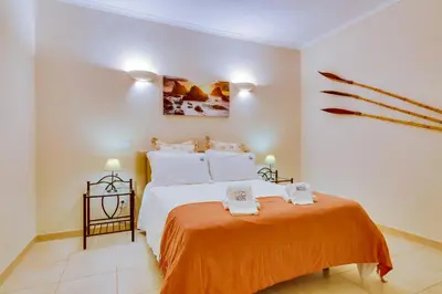 a bedroom with a bed with an orange blanket at Falésia Nature Villa by The Portuguese Butler in Albufeira