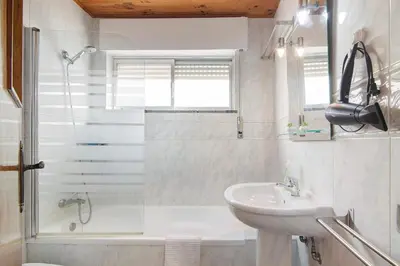 a white bathroom with a sink and a shower at Matinhos House in Faro