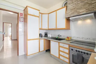 a kitchen with white cabinets and a stove at Matinhos House in Faro