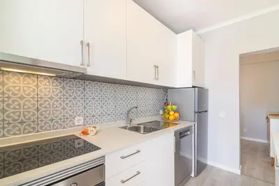 a kitchen with white cabinets and a stainless steel refrigerator at Vilamoura - MAGNÓLIA 512 - T1 in Vilamoura