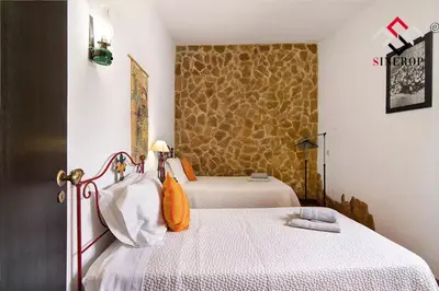 a bedroom with two beds and a stone wall at Villa Tigonema in Albufeira