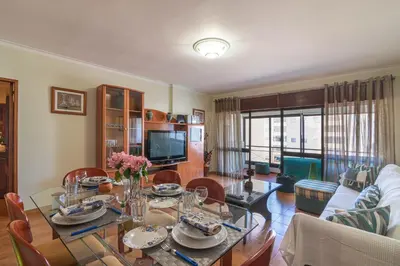 a living room with a table and a dining room at Quarteira CONDESTÁVEL T3 in Quarteira