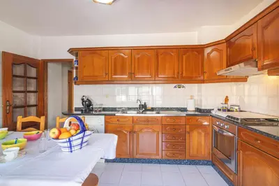 a kitchen with wooden cabinets and a bowl of fruit on a table at Quarteira CONDESTÁVEL T3 in Quarteira