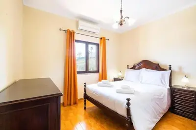 a bedroom with a bed and a window with orange curtains at Villa Camila - Ideal location ten-min walk to Albufeira Marina in Albufeira
