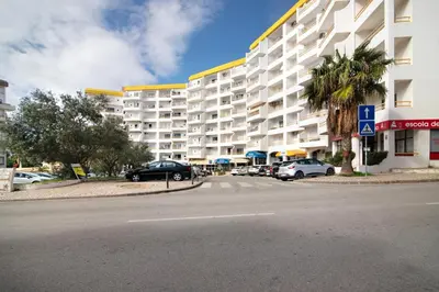 a large white building with cars parked next to a street at T1 Marques in Albufeira