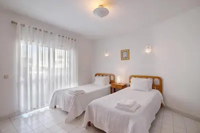 two beds in a white room with a window at Apartamento T1 Antonio Henriques in Albufeira