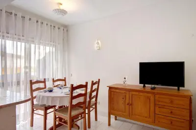 a dining room with a table and a television on a dresser at Apartamento T1 Antonio Henriques in Albufeira