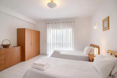 a bedroom with two beds and a cabinet and a window at Apartamento T1 Antonio Henriques in Albufeira