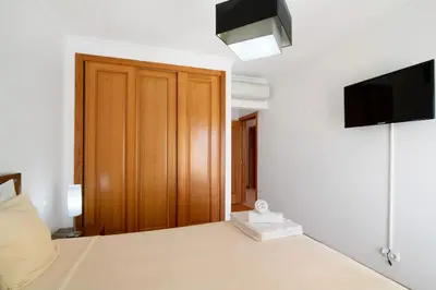 a bedroom with a bed with a wooden closet and a television at T2 Tubio in Albufeira