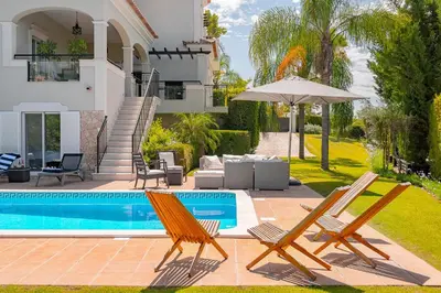 a villa with a swimming pool and two chairs and an umbrella at Villa Simone in Almancil