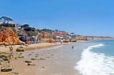 a beach with people standing in the water at D'Água Brisa beachside apartment in Albufeira