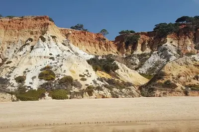 a rocky mountain with a beach in front of it at Magnifique Duplex avec piscine en bord de mer in Olhos de Água