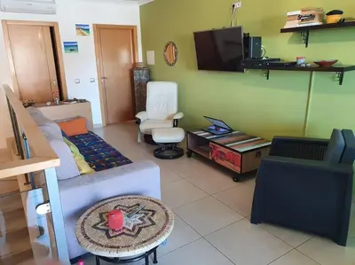 a living room with a couch and a tv at Magnifique Duplex avec piscine en bord de mer in Olhos de Água
