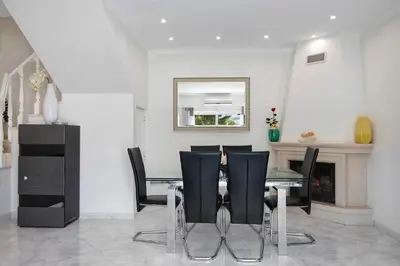a dining room with a glass table and black chairs at Vila Alonzo in Albufeira