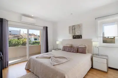 a white bedroom with a bed and a mirror at Vila Alonzo in Albufeira