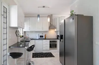 a kitchen with white cabinets and a stainless steel refrigerator at Vila Alonzo in Albufeira