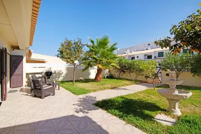 a patio with chairs and a fountain in a yard at Vila Alonzo in Albufeira