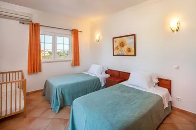 a room with two beds and a window and a crib at 4 Bed Private Villa Ribeiro II with heated pool, garden, wi-fi in Albufeira