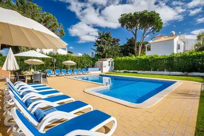 a pool with chairs and an umbrella and a swimming pool at VTII & VTI 2 X Private Villas with pool and garden in Albufeira