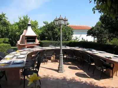 a long wooden table with chairs and a grill at CH 7 - One Bedroom Apartment, Casa da Horta, Pool and Garden in Albufeira