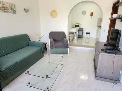 a living room with a green couch and a television at CH 7 - One Bedroom Apartment, Casa da Horta, Pool and Garden in Albufeira
