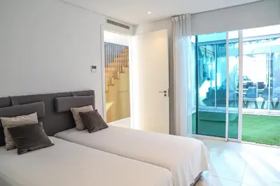 two beds in a white room with a window at Villa Central By Garvetur in Quarteira