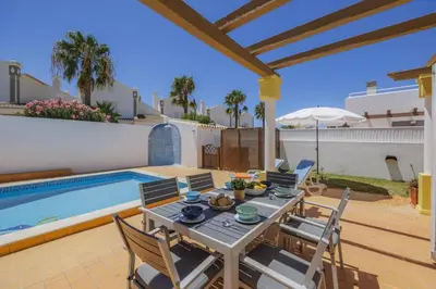 a patio with a table and chairs next to a swimming pool at Villa Algarhb by Villa Plus in Albufeira